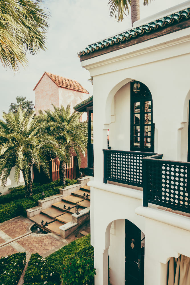 fatada casa alb cu negru, arcade ferestre, balcon, palmieri, trepte